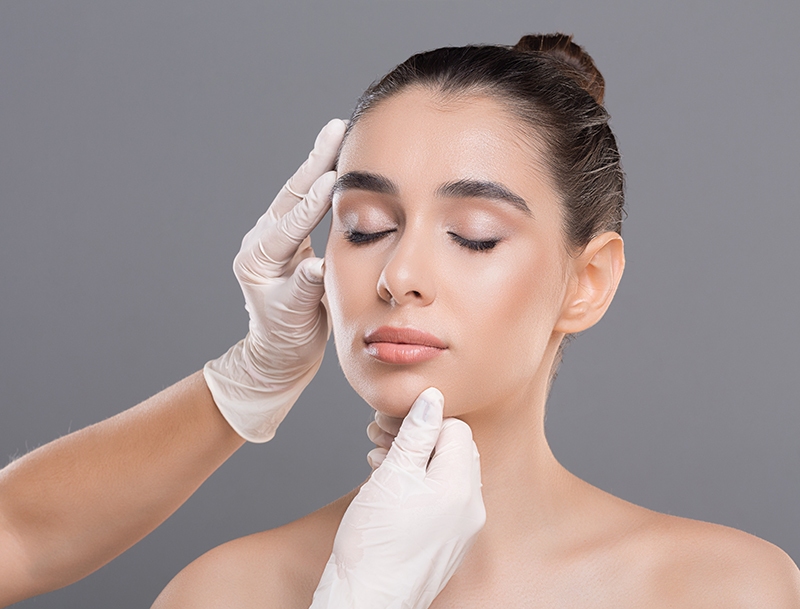 doctor in white gloves touching her face